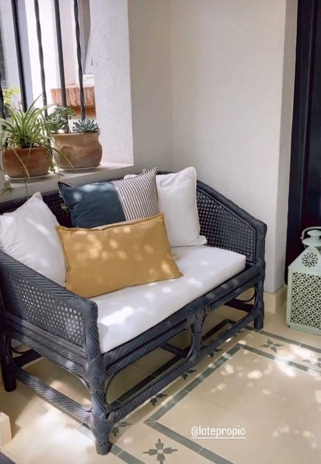 Almohadón mostaza lumbar sobre sillón de mimbre